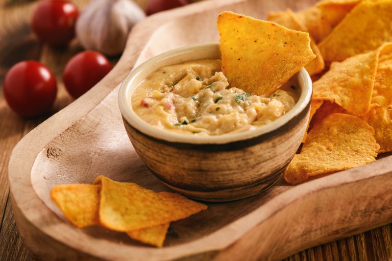 Crab and green chile queso dip served warm with tortilla chips on the side