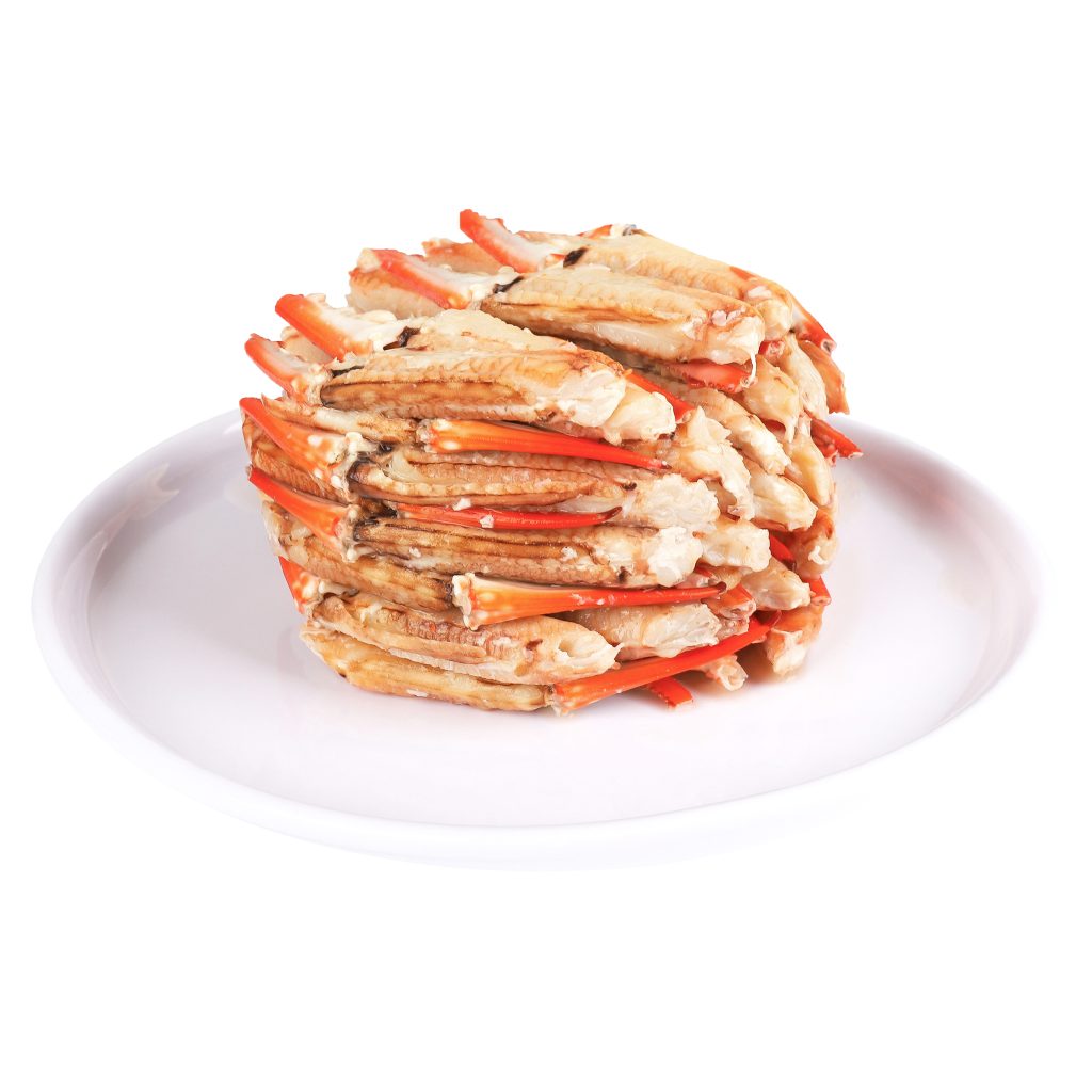 Stack of crab legs arranged on a white plate against a white background.