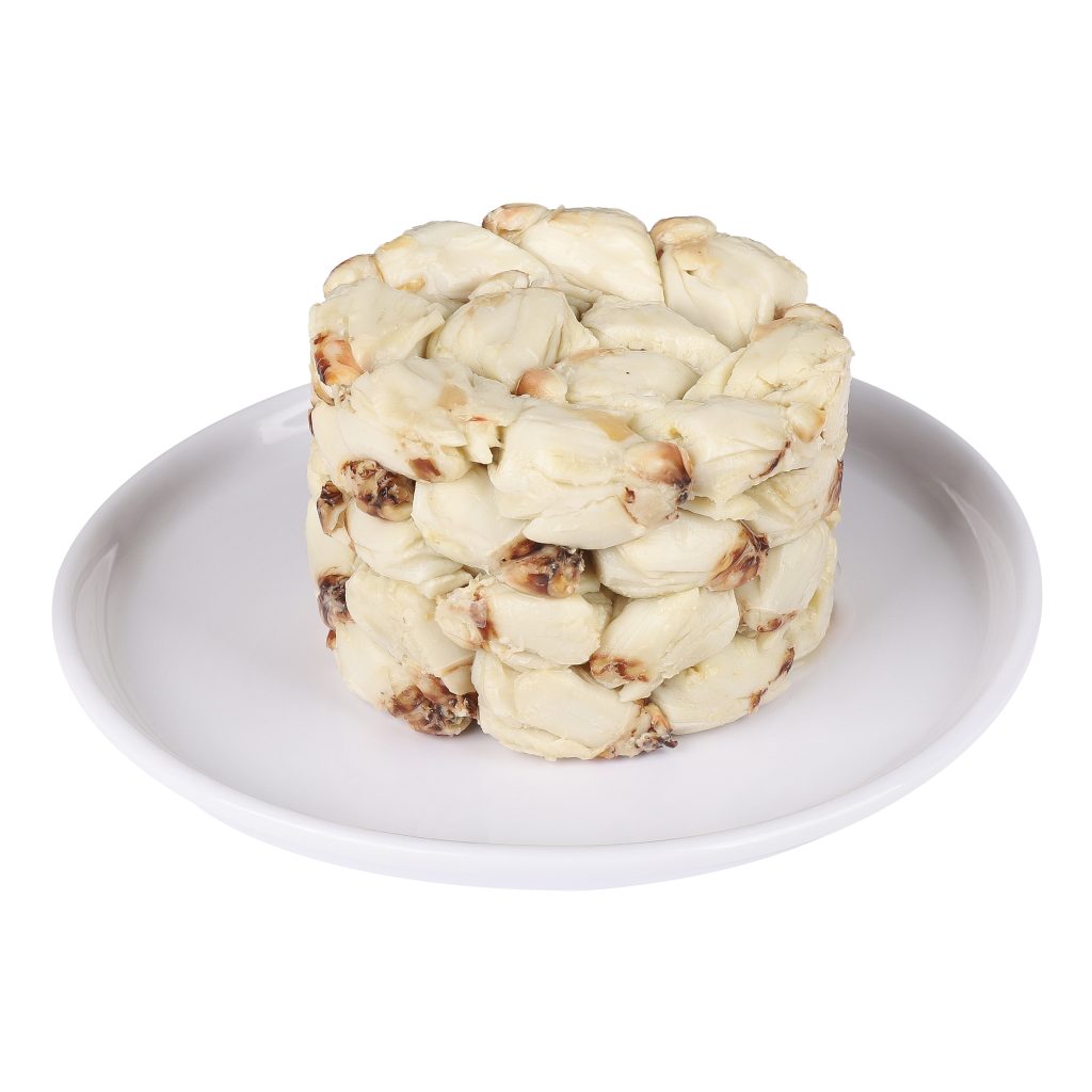 A stack of white crab meat arranged in a round shape on a white plate, against a white background.
